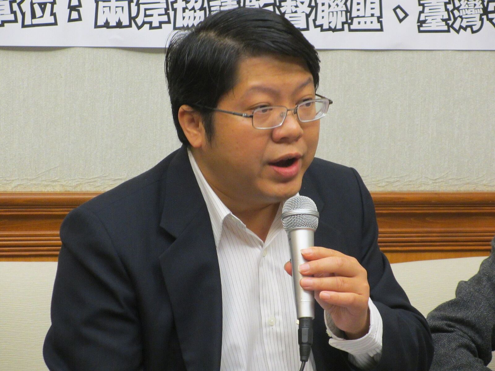 A man speaks into a microphone at a business event, demonstrating effective communication.