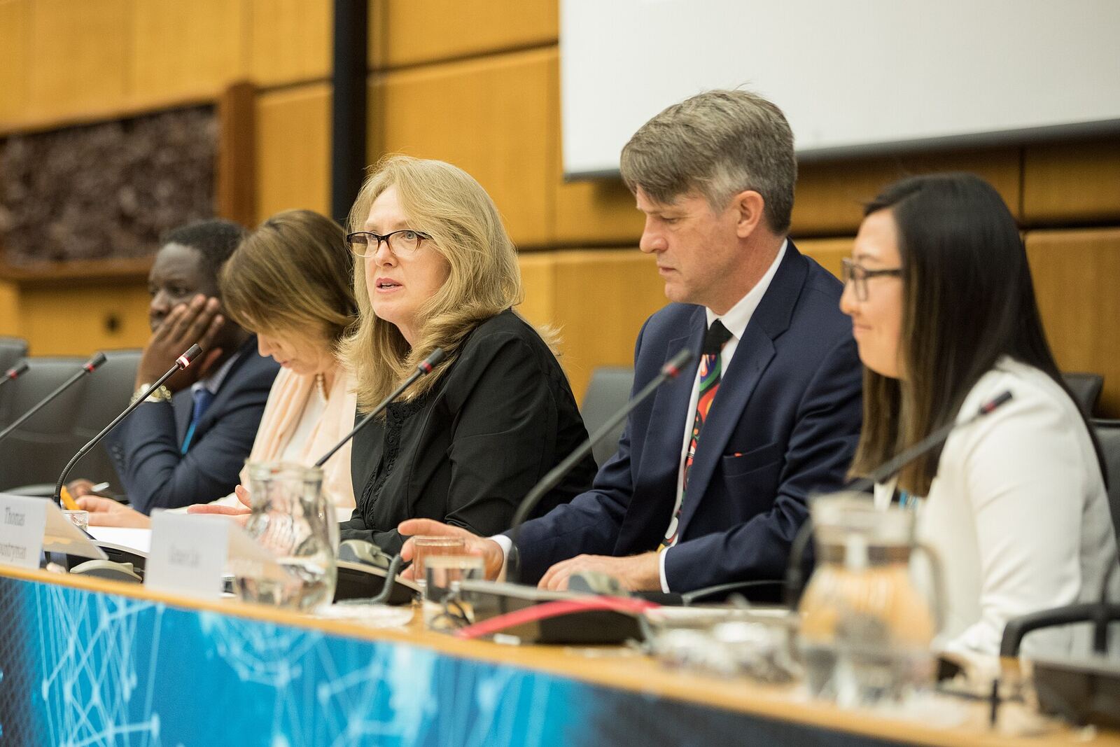 Panel members speak at a formal event, demonstrating effective communication during a discussion.