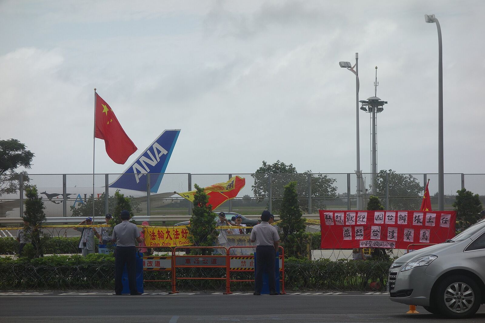 An airport entrance in Taiwan welcomes a delegation, with flags and an airplane tail sculpture visible.