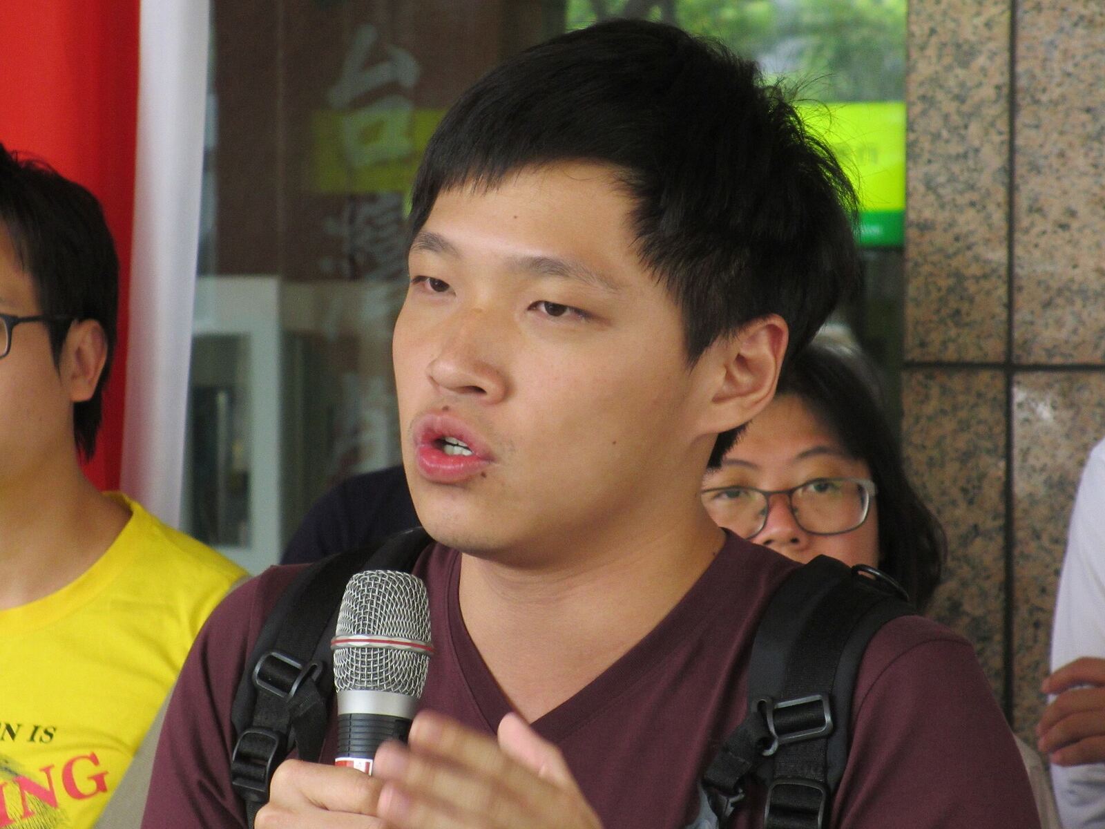 A young man speaks into a microphone at an outdoor protest, demonstrating effective communication.