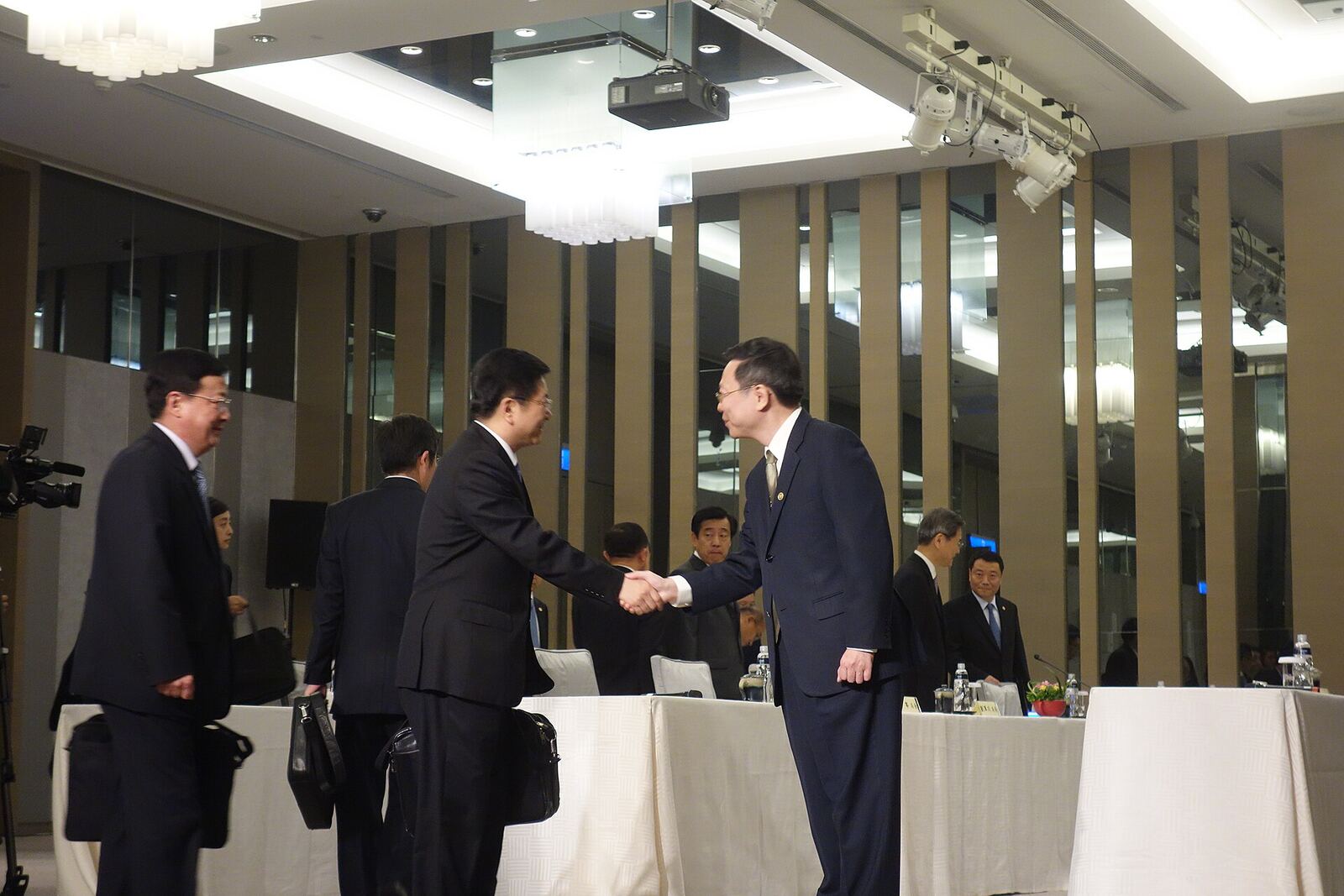 Wang-Zhang Meeting | Some Tact Two businessmen shake hands during the 2014 Wang-Zhang Meeting, demonstrating effective conflict resolution.