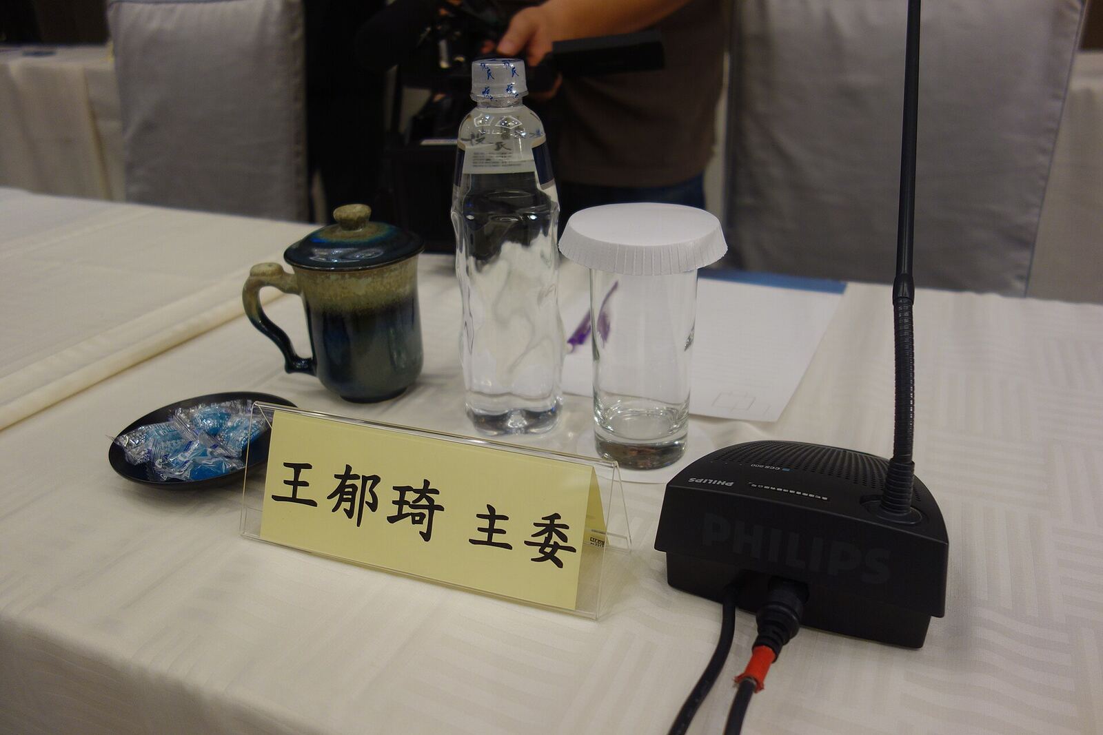A conference table with a nameplate and microphone from the 2014 Wang-Zhang Meeting, illustrating conflict resolution.